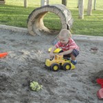 child with dumptruck in sand