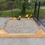 Wood Sided Sandbox filled with Gravel and Dump Trucks